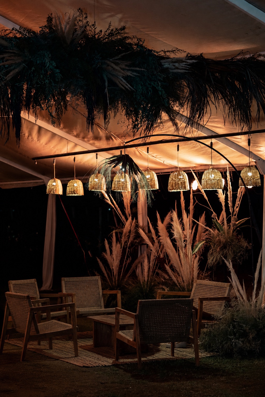 Lounge de evento al atardecer: lámparas de mimbre, follaje colgante y pampa grass